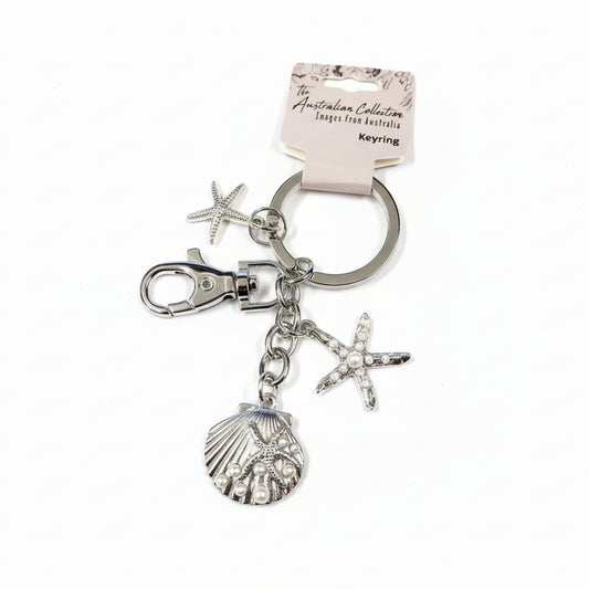 Silver keychain with starfish and shell charms on a light gray background